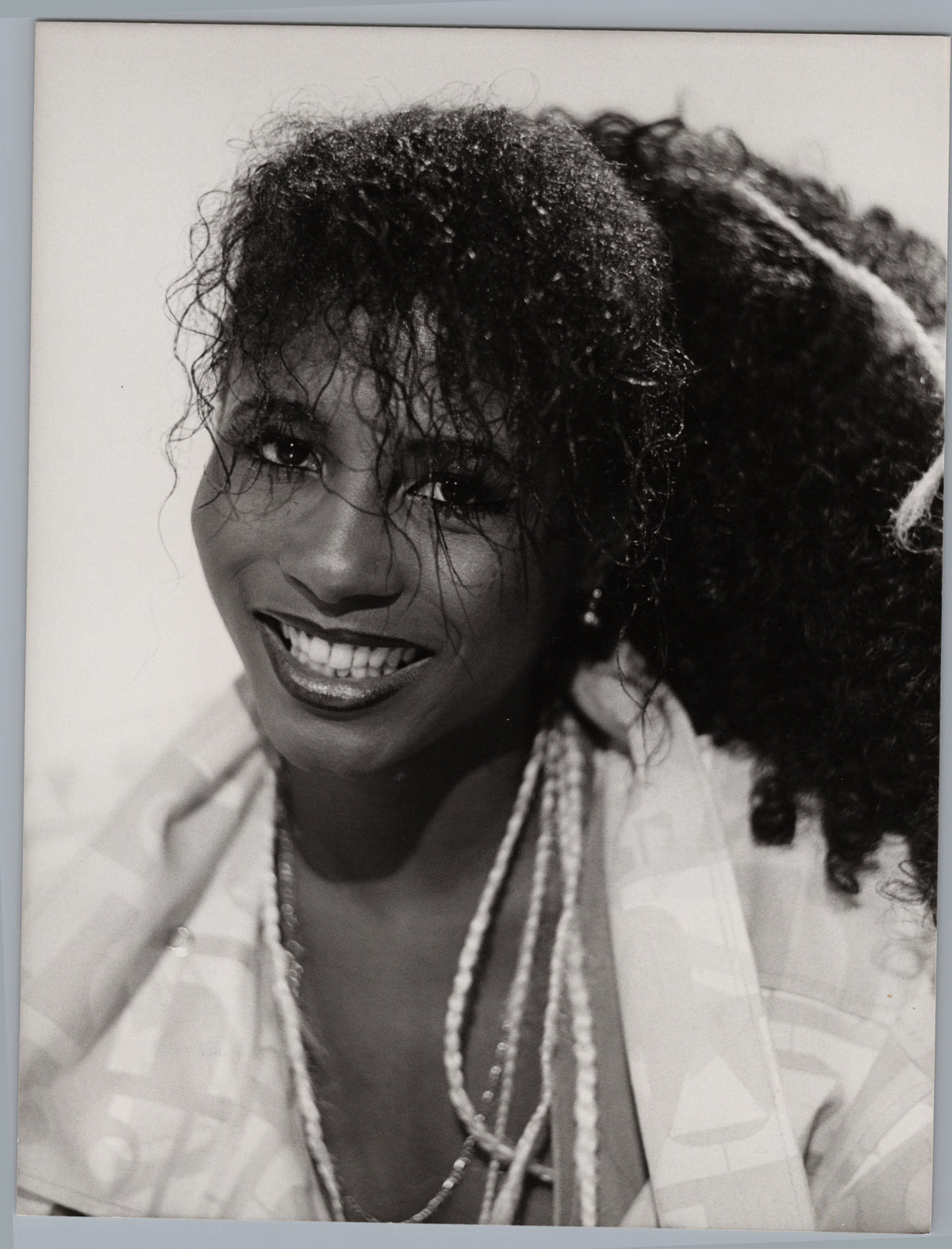 Sinitta — Smiling Portrait with Layered Necklaces — front