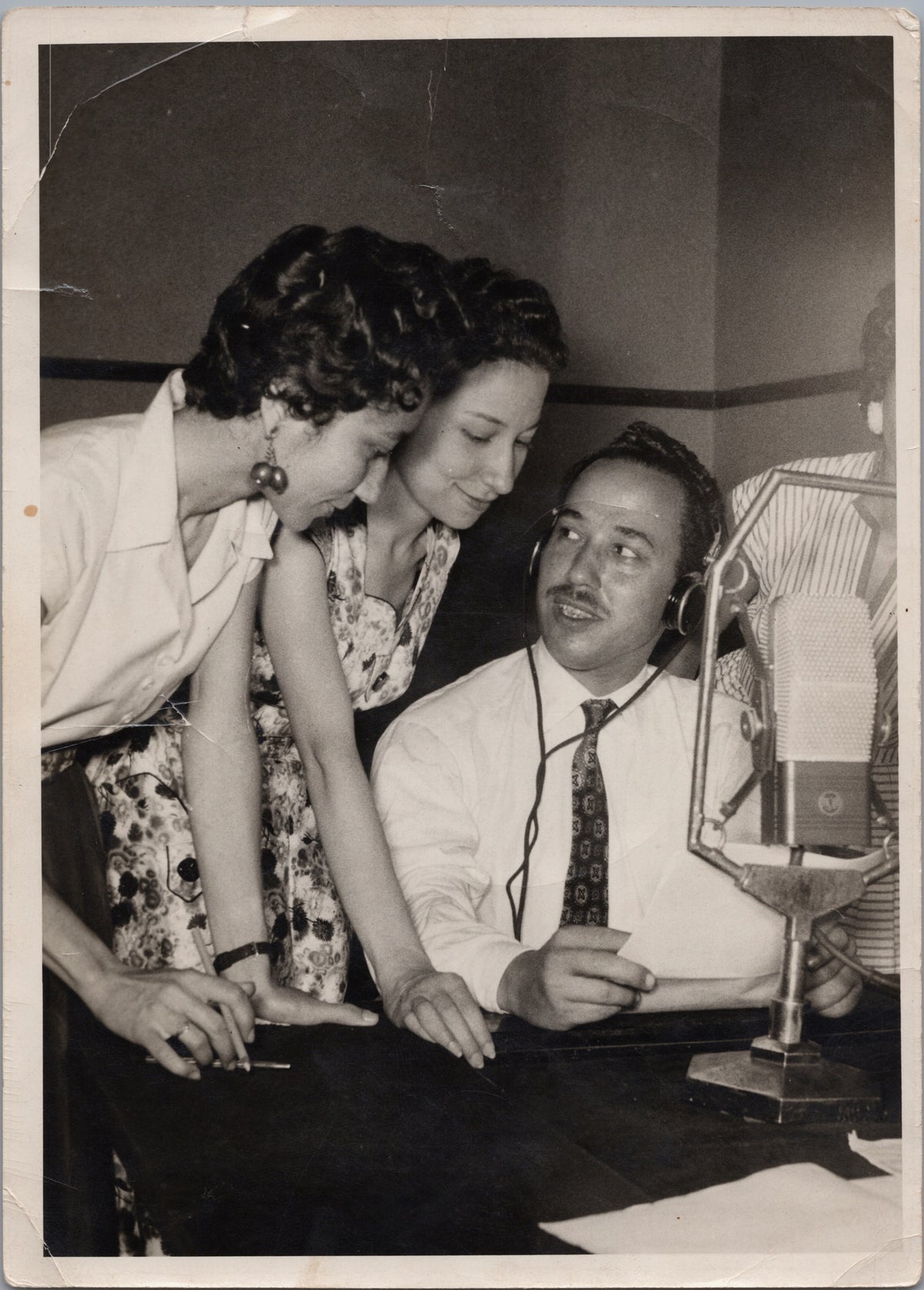 Three People Gathered Around a Recording Microphone — front